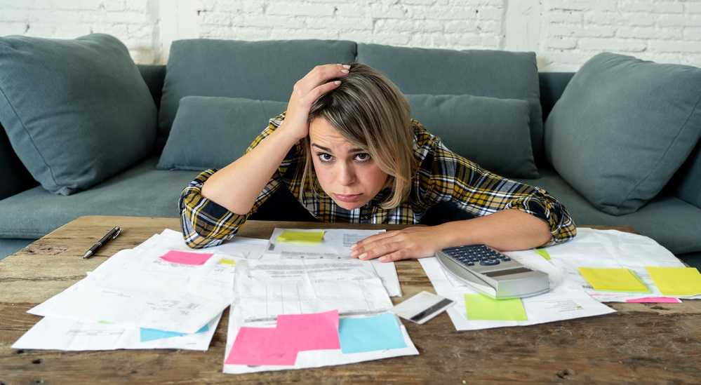 How to Pay Off Debt Fast on a Low Income: A woman is sitting at a table with a lot of papers on how to pay off debt fast on a low income.
