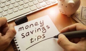 A pen jotting down tips on how to save money next to a keyboard.