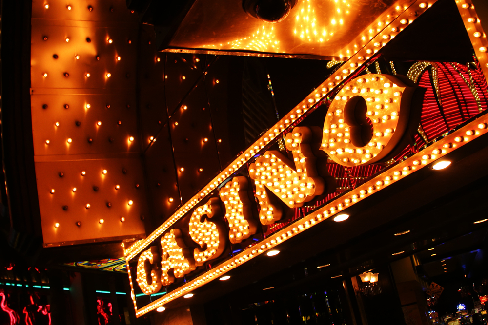 A casino sign, lit up at night, beckoning with its promises of wealth and temptation. Money Habits That Can Make You Poor