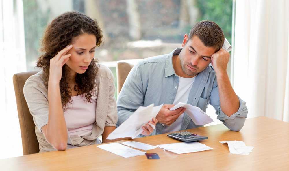 A couple sitting at a table, engrossed in examining papers related to debt consolidation.
