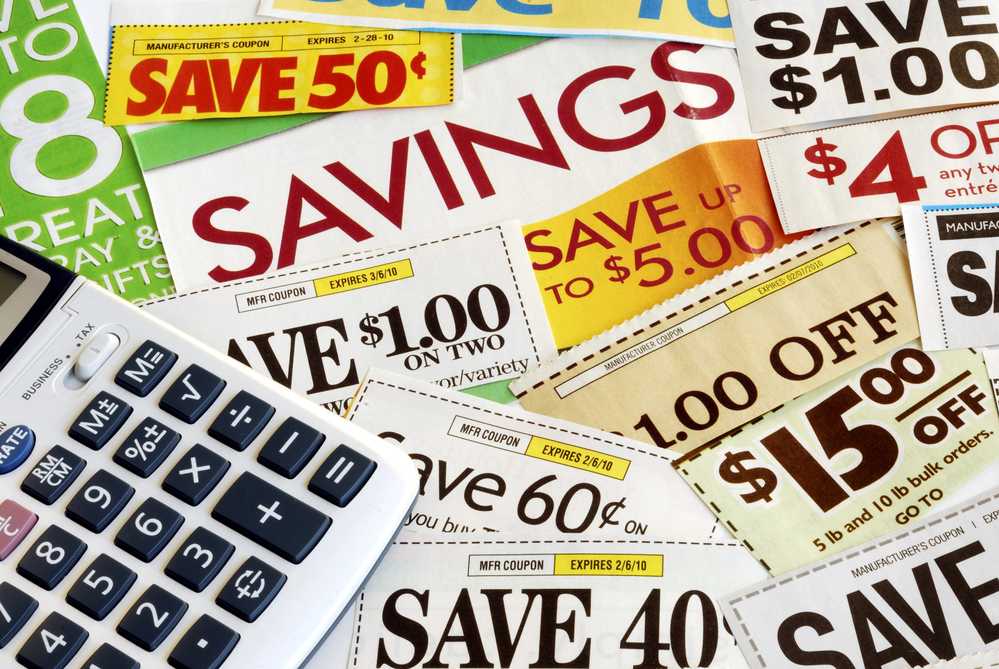 A calculator next to a pile of coupons, demonstrating frugal money-saving techniques.